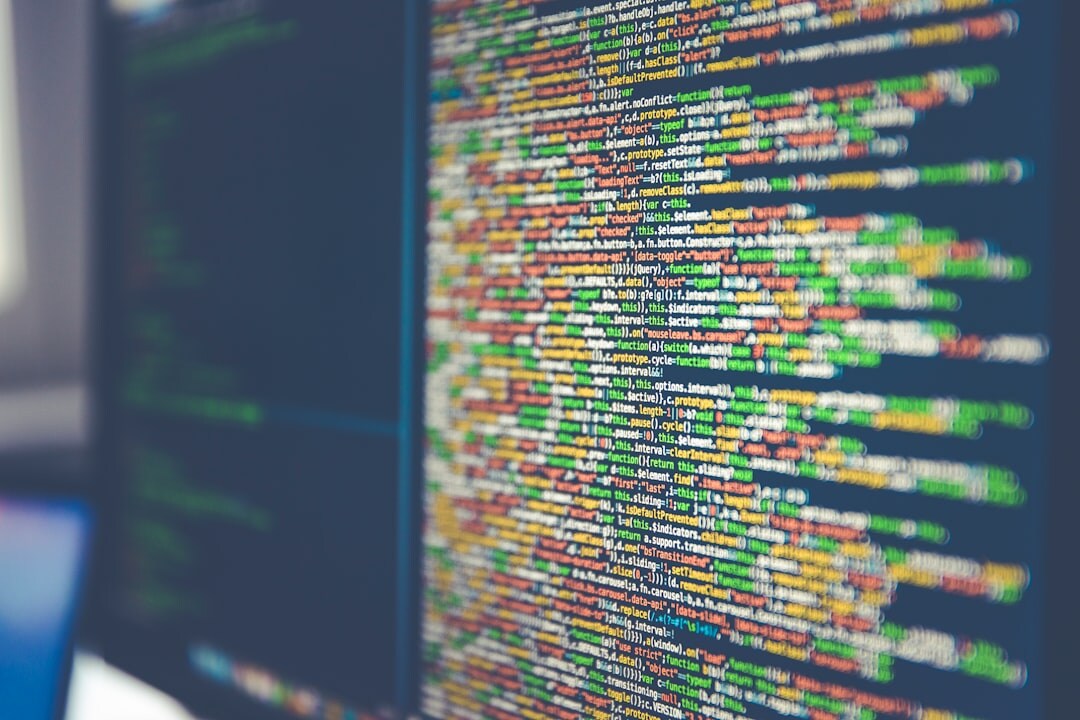 Software developer coding on multiple monitors with colorful code